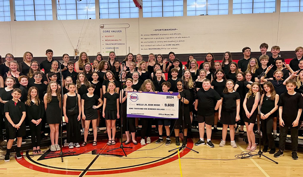 Wells Jr. High School Music Department posing in front of a cheque of $9,600 from the mattress fundraiser