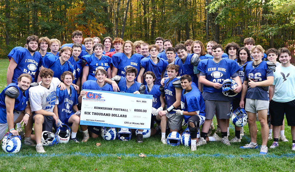 A group of students on the football team posing infront of a $6,000 cheque from the mattress fundraiser